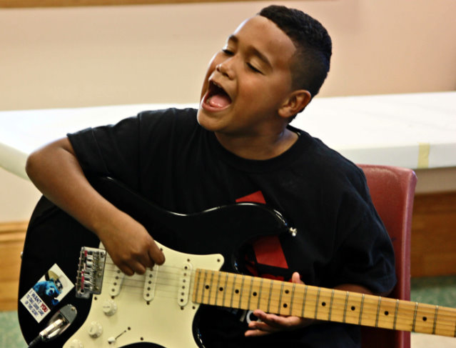 Youth student playing guitar in the Tenderloin Recreation Center